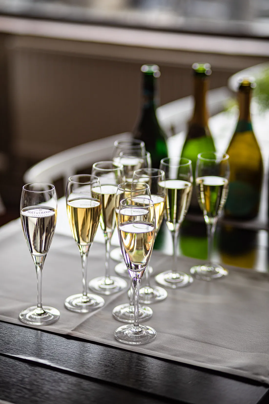 Flera fyllda champagneglas uppställda på en vit duk, redo för servering vid en tillställning.